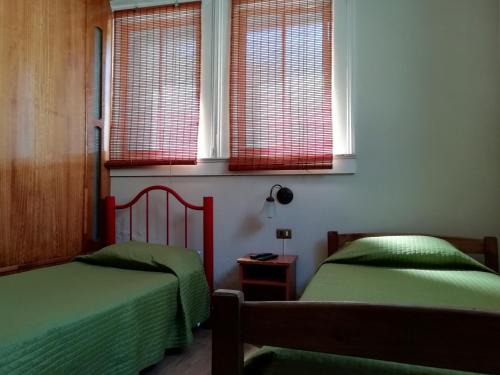 deux lits dans une chambre avec deux fenêtres dans l'établissement Hostal Dinamarca, à Valparaíso