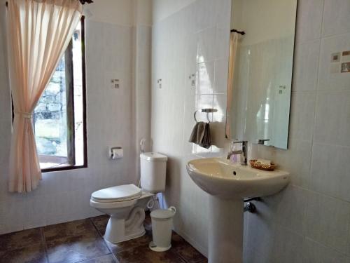 a white bathroom with a toilet and a sink at Woodlawn Villas Resort in Ko Tao