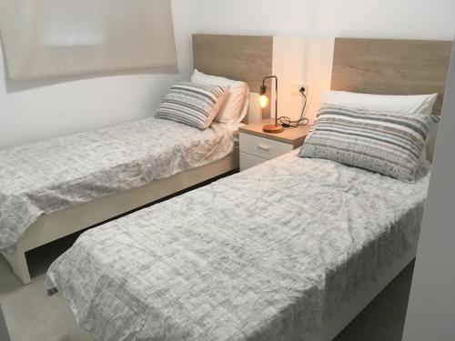 a bedroom with two beds and a lamp on a night stand at Apartment "Las Palmeras" in Los Alcázares