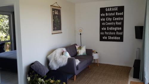 a living room with a couch and a sign on the wall at Four Huia in Oneroa