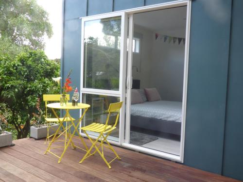 a patio with a table and chairs and a bedroom at Four Huia in Oneroa