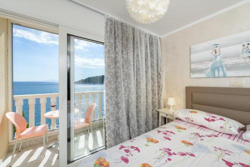 a bedroom with a bed and a balcony with the ocean at Luxury Bellavista Amazing sea Holidays with Private Beach & Parking in Milna