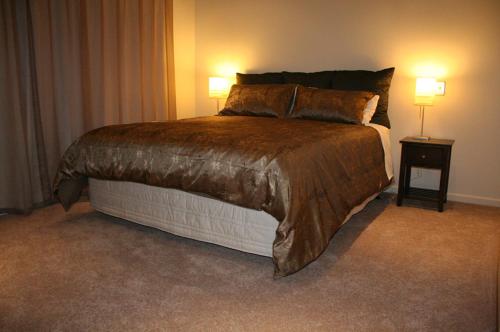 a large bed in a room with two lamps at Pine Hill Lodge In Vineyard in Mapua