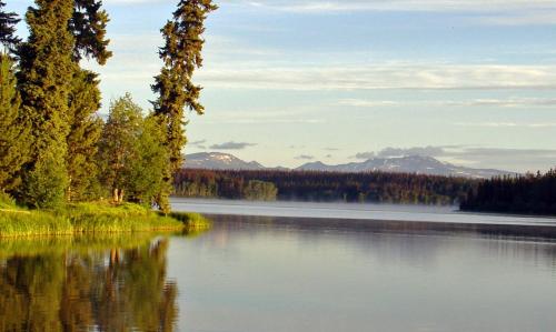 een meer met bomen en bergen op de achtergrond bij Eagle's Nest Resort in Anahim Lake