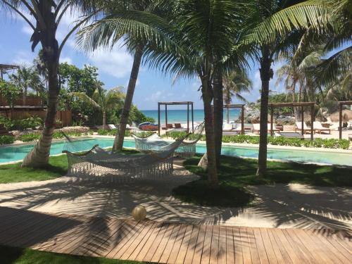 a resort with a hammock and a pool with palm trees at Maria Del Mar Tulum - Adults Only in Tulum
