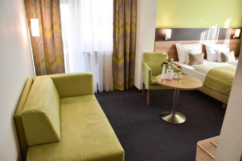 a hotel room with a bed and a table and a couch at Martins Klause Airport Messe Hotel - Air Conditioning - Self Check-In available in Leinfelden-Echterdingen