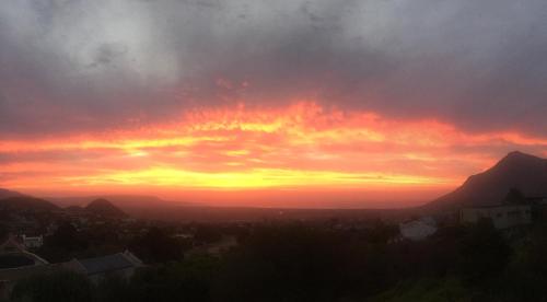 a sunset over a city with mountains in the background at Sapphire Studio in Noordhoek