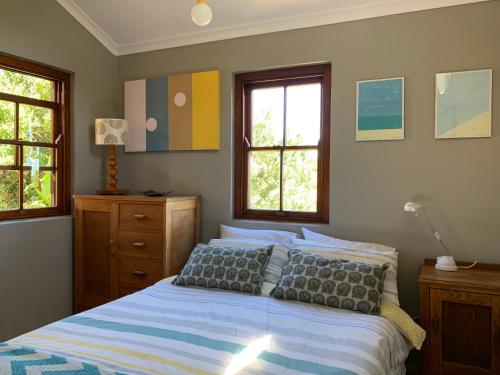 a bedroom with a bed and two windows at Sapphire Studio in Noordhoek