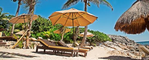 a group of chairs and umbrellas on a beach at Maria Del Mar Tulum - Adults Only in Tulum