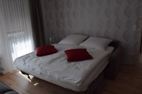 a white bed with two red pillows on it at Gästehaus Sylvia in Kelberg