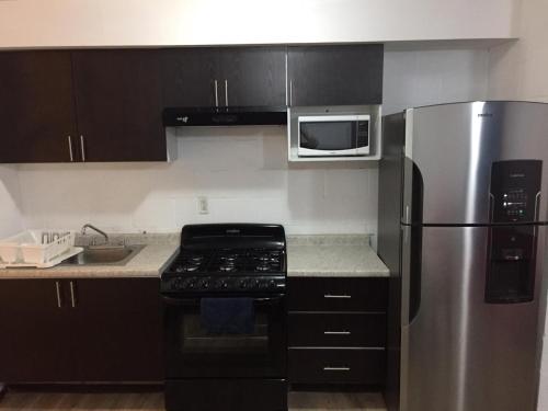 a kitchen with a stove and a stainless steel refrigerator at Bonito Departamento en el Centro de Guadalajara in Guadalajara