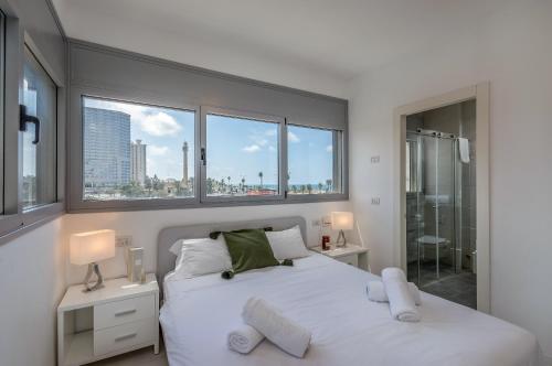 a bedroom with a white bed with a view of the city at Beautiful Sunny 3 bedrooms in font of the beach in Tel Aviv