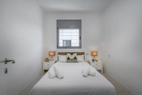 a white bedroom with a large bed and a window at Beautiful Sunny 3 bedrooms in font of the beach in Tel Aviv
