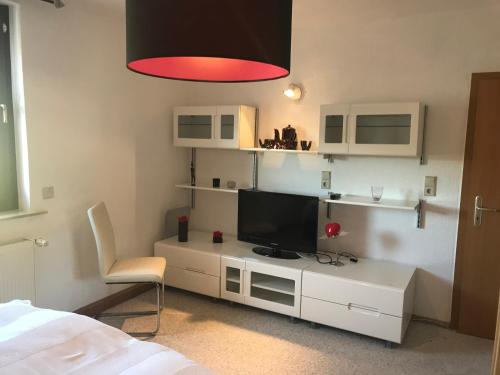 a living room with a tv on a white cabinet at Ferienhaus zur Waldauer Höhe mit 3 SZ, 120qm & 40qm Balkon in Schleusingen