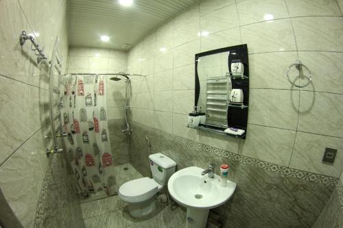 een badkamer met een wastafel, een toilet en een spiegel bij "METROPOL" APARTMENT HOTEL in Baku