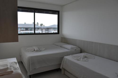 a room with two beds and a window at Boutique Ecolife in Porto De Galinhas