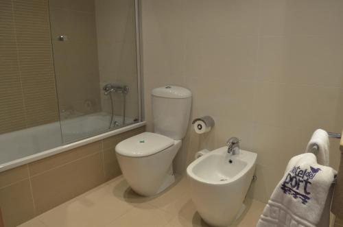 a white bathroom with a toilet and a sink at Hotel del Port in Sant Carles de la Ràpita