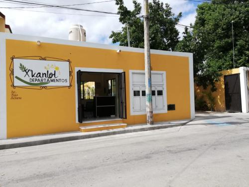 a yellow building with a sign on the side of it at Departamentos X`Kanlol in Izamal