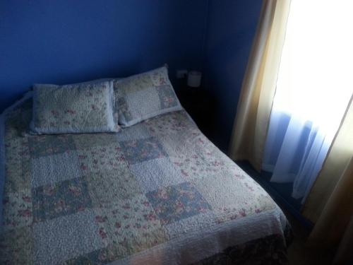 a bedroom with a bed with a quilt and a window at Departamento a minutos del centro in Puerto Montt