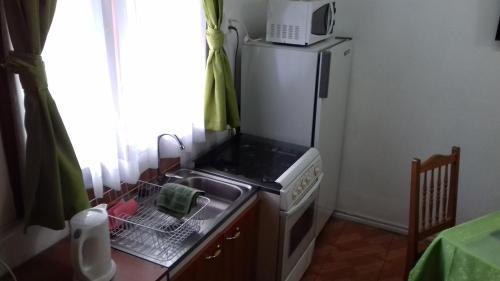 a kitchen with a refrigerator and a sink and a microwave at Departamento a minutos del centro in Puerto Montt