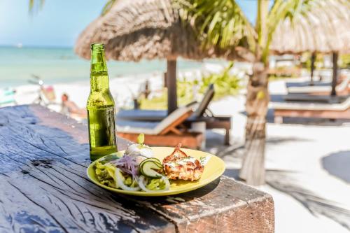 a plate of food and a bottle of beer on a table near the beach at Zomay Beachfront Holbox in Holbox Island