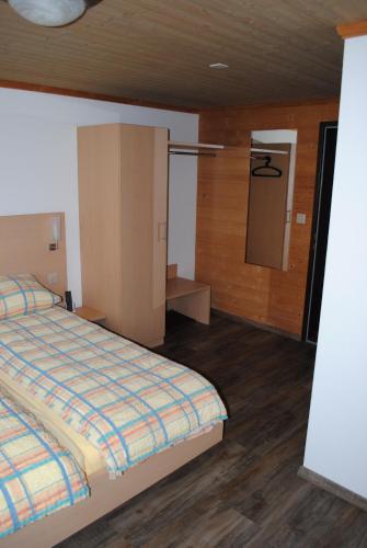 a bedroom with a bed and a small bathroom at Hotel Des Alpes in Kandersteg