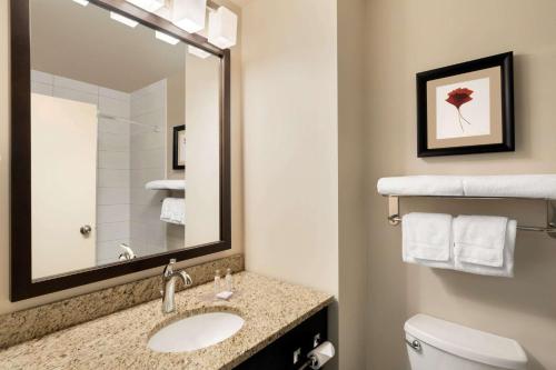 a bathroom with a sink and a toilet and a mirror at Travelodge Hotel by Wyndham Weyburn in Weyburn