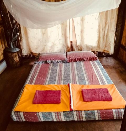 a bedroom with a bed with two pillows on it at Shanti Farm in Tha Kradan