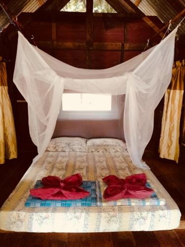 Una cama con dosel con dos arcos rojos. en Shanti Farm, en Tha Kradan