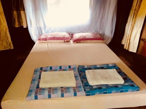 Cama en habitación con ventana y 2 toallas en Shanti Farm, en Tha Kradan