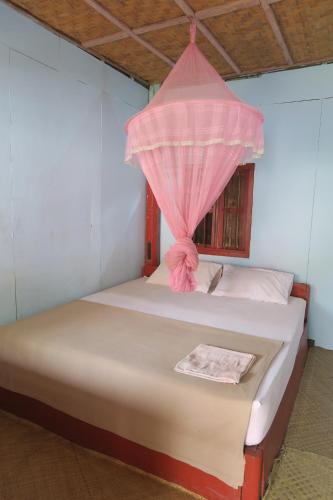 um quarto com uma cama e uma rede mosquiteira rosa em Ning Ning Bungalow em Don Det