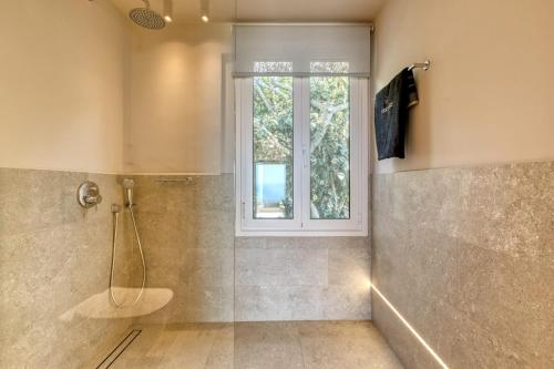 a bathroom with a shower and a window at Artblue Villas in Tsoukaladhes