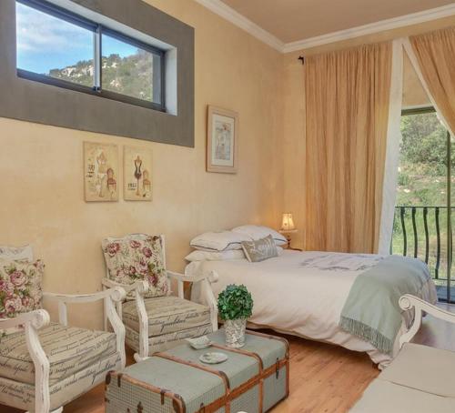 a bedroom with a bed and two chairs and a window at Casa a Capri, Capri Village, Cape Town in Fish hoek