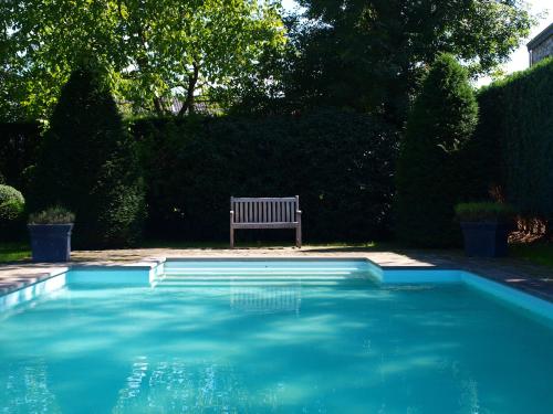 a bench sitting next to a blue swimming pool at B&B La Buissonniere in Xhoris
