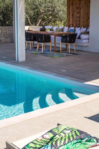 a table and chairs next to a swimming pool at Artblue Villas in Tsoukaladhes