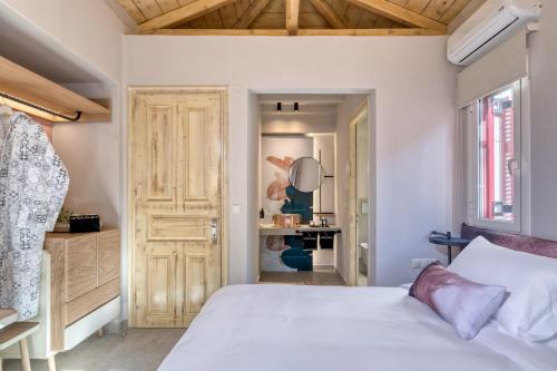 a bedroom with a white bed and a wooden door at Artblue Villas in Tsoukaladhes