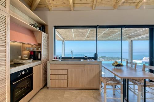 a kitchen with a dining table and a large window at Artblue Villas in Tsoukaladhes