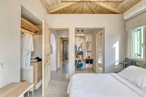a bedroom with a white bed and a wooden ceiling at Artblue Villas in Tsoukaladhes