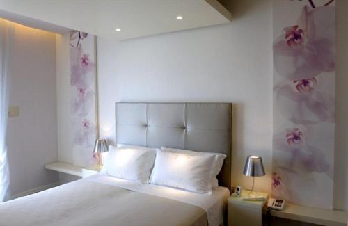a bedroom with a white bed with pink flowers on the wall at Hotel Torremaura in Milano Marittima