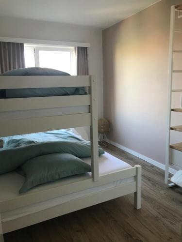 a white bunk bed in a room with a window at Castel aan zee in Koksijde