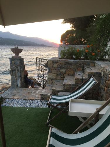 a couple of lawn chairs sitting next to the water at Roditses Beach Sea Front Apartments in Samos