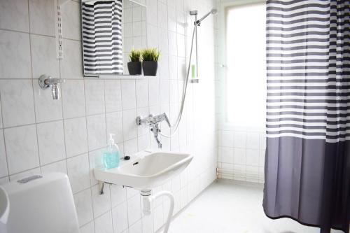 a white bathroom with a sink and a toilet at Hiisi Homes Lohja in Lohja