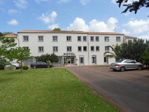 een groot wit gebouw met auto's geparkeerd voor het bij hotel l'échappée d'oléron in Saint-Georges-dʼOléron