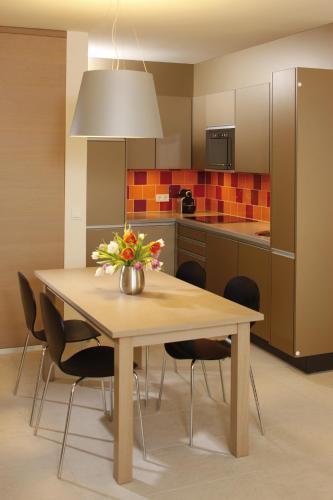 a kitchen with a wooden table with chairs and a vase of flowers at Hapimag Ferienwohnungen Hörnum in Hörnum