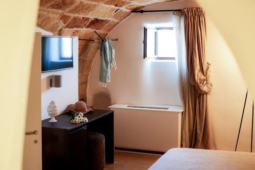 a room with a bed and a television and a window at Aquamarea in Polignano a Mare