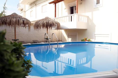 una piscina con 2 sombrillas junto a un edificio en Kouros Chania Villas, en Máleme