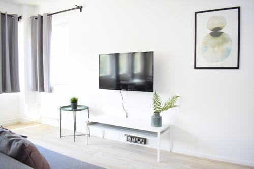 a living room with a flat screen tv on a white wall at Hiisi Homes Helsinki Haaga in Helsinki