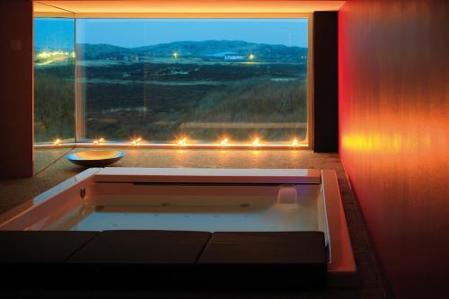 a bath tub in a room with a large window at Hapimag Ferienwohnungen Hörnum in Hörnum