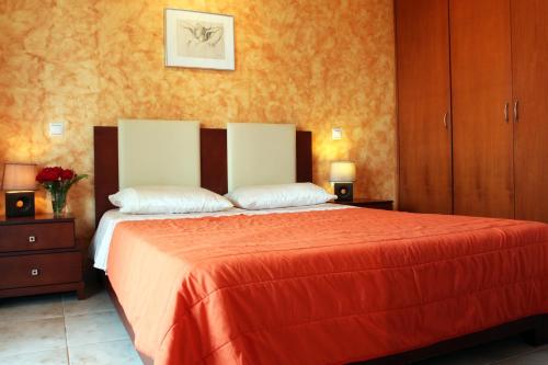 1 dormitorio con 1 cama grande con sábanas de color naranja en Kouros Chania Villas, en Máleme