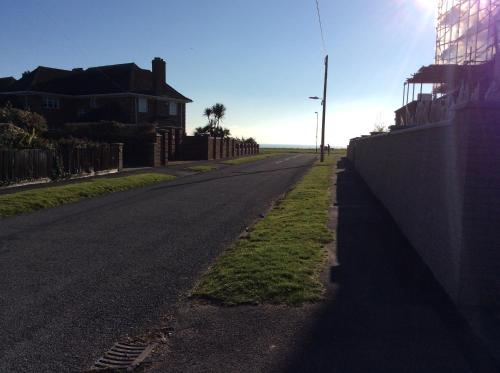 an empty street with a fence on the side of the road at Cliff Top Studio in Barton on Sea